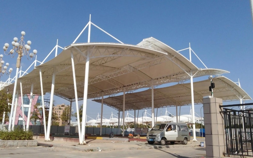 Multi-bay white architectural tensile canopy structure on steel tripod masts