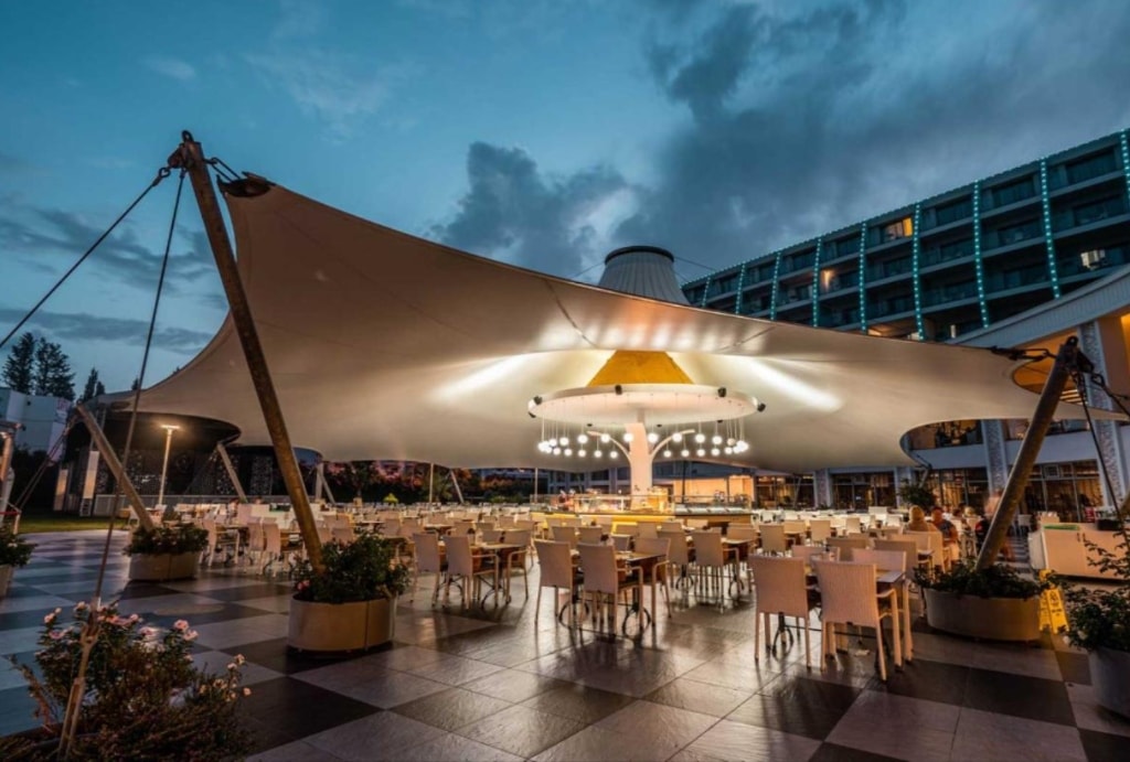 Column-free covered open space beneath tension canopy
