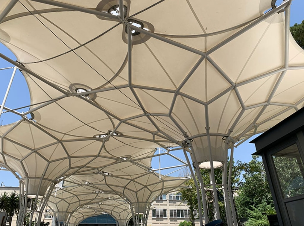 Modular geometric tensile umbrella canopy structure over courtyard